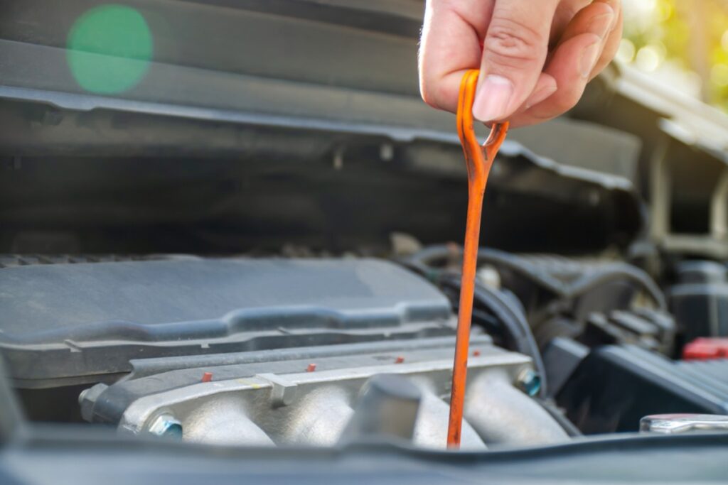 Pretending to be an expert mechanic by checking oil with greasy hands at the pump