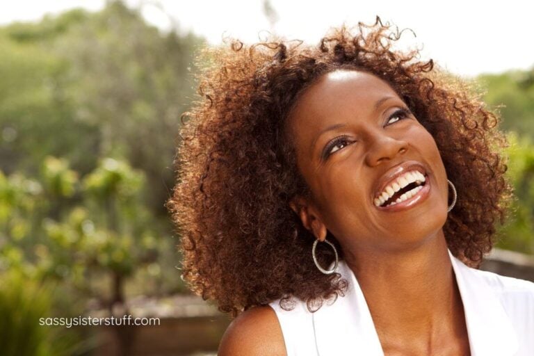 beautiful African American woman looks up into the sky and laughs.