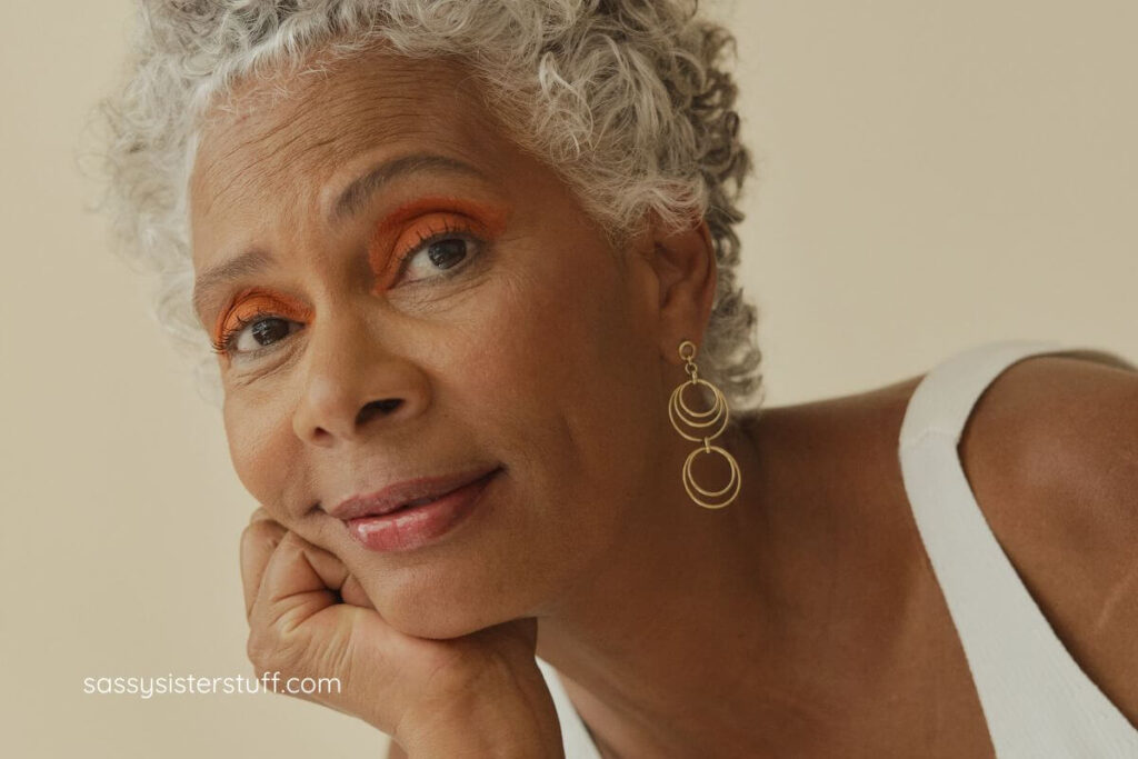 close-up of a lovely African American smiles into the camera as she rests her chin on her hand.