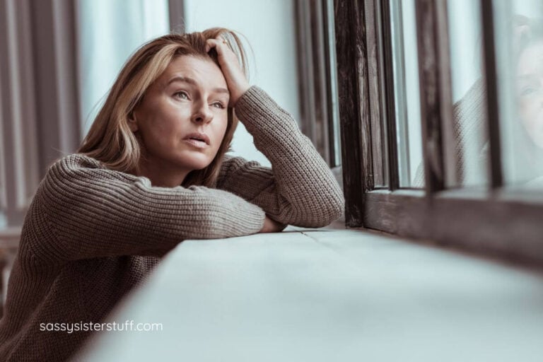very sad midlife woman looking out a window with tears in her eyes.