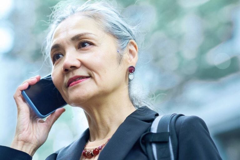confident midlife female dressed in business clothes talks on the phone.
