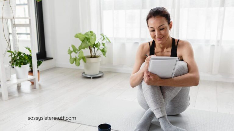 woman sitting on a yoga mat taking notes in her journal about what is personal growth.