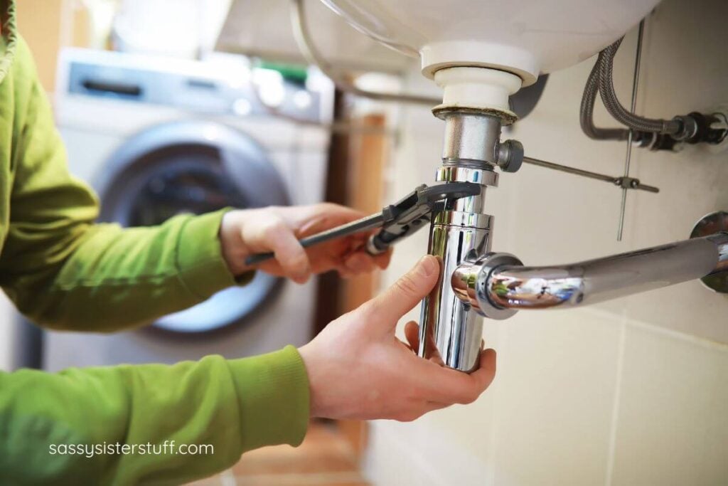 female hands repairing a drain pipe under a sink.