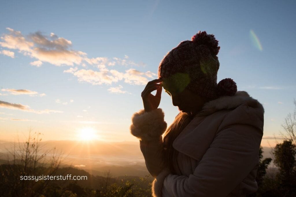 silhouette of a woman with her hand to her forehead thinking in the early morning sunlight.