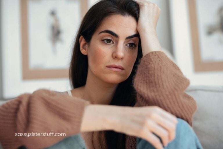 middle aged pretty woman sitting with her elbow propped on her bended knees appearing to be stuck in her thoughts.