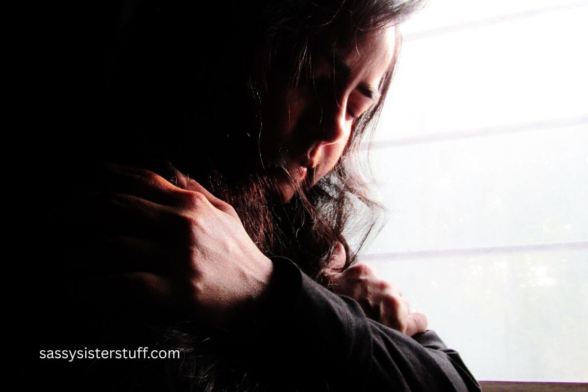 midlife woman leaning against a window feeling lonely.