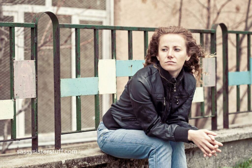 woman sitting on a concrete wall feeling sad but not able to recognize when you're lonely.