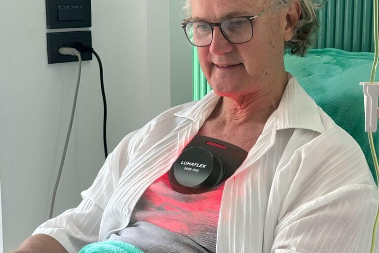 a woman sitting in a hospital chair with a lumaflex red light therapy device on her chest