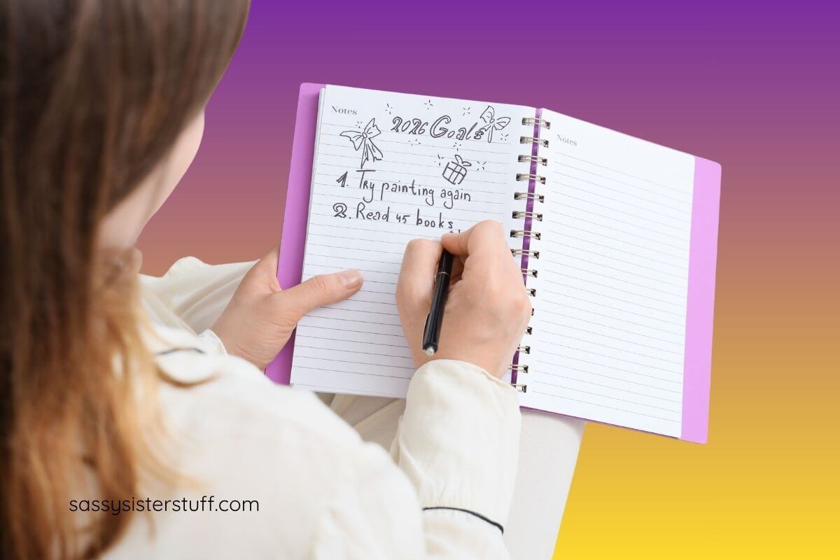 partial image of a woman who is writing down her yearly goals in a journal.