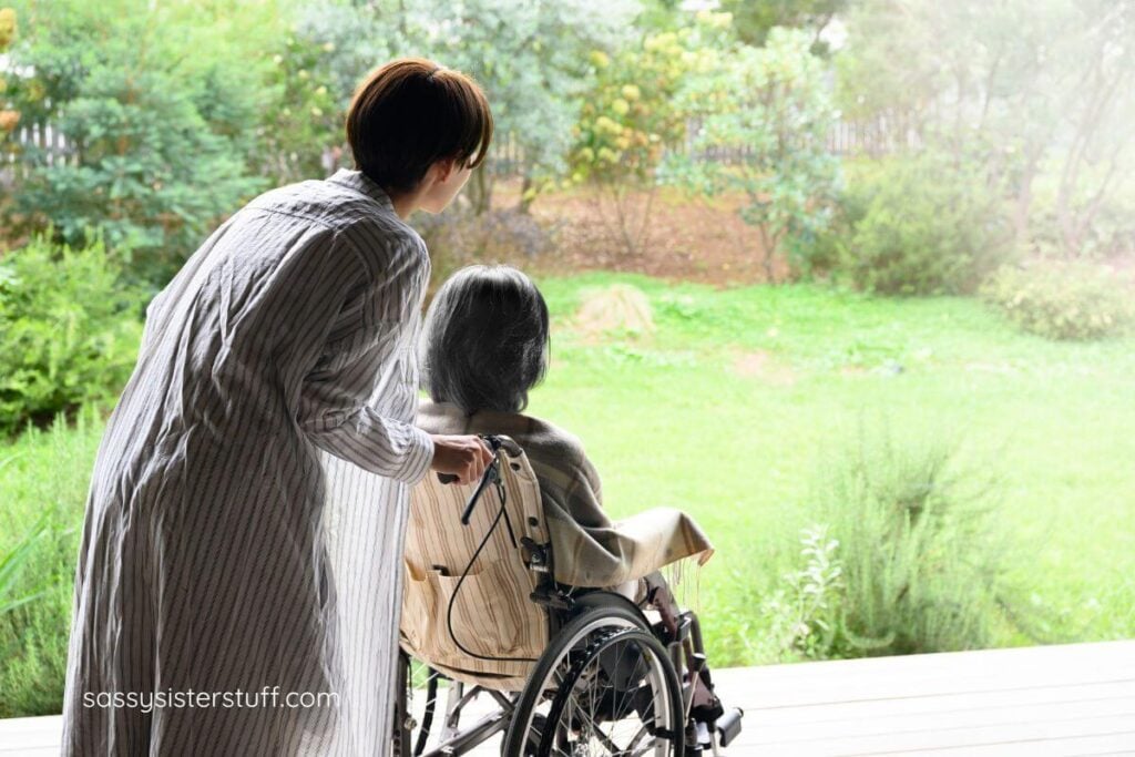 elderly mom in a wheelchair is pushed by her adult daughter in a beautiful green garden.