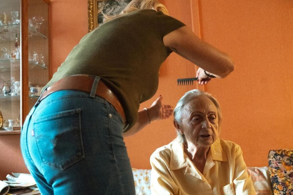 an adult daughter does her mother's hair.