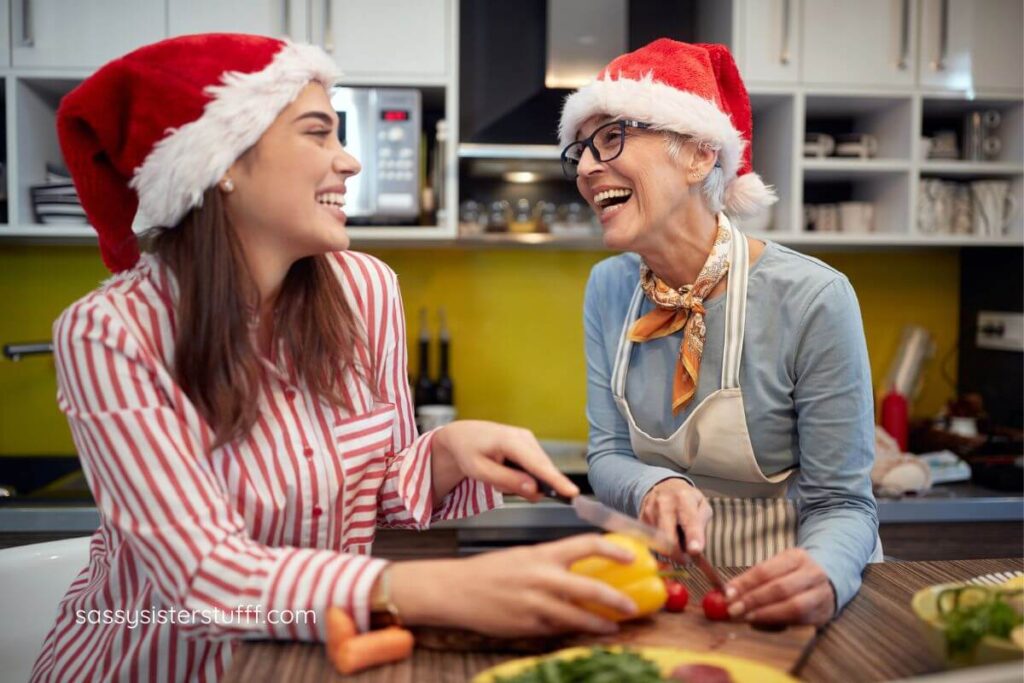 elderrly mother and adult daughter managing stress as a caregiver during the holiday season working together in the kitchen laughing and having fun.