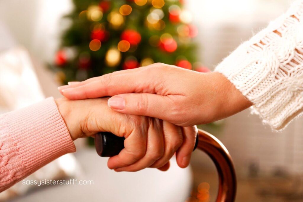 close up of hand on a cane, with another hand on top of it and a Christmas tree in the background.