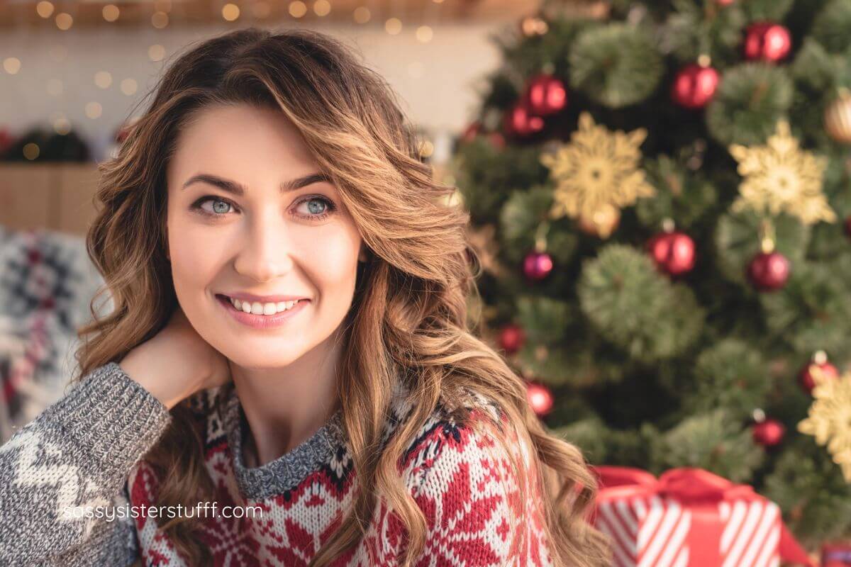 midlife woman who is managing stress as a caregiver duing the holiday season is relaxing in front of a Christmas tree