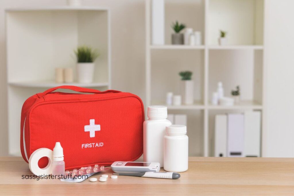 a red first aid bag sits on a table with a thermometer and bottles of pills.