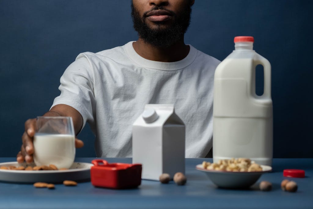 Close-up of a man with almond milk options and nuts on a table, promoting a healthy lifestyle.