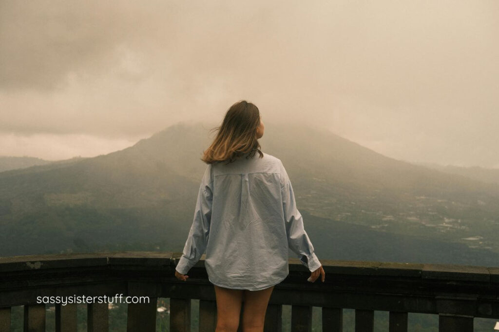 female standing on a balcony breathing in the mountain air.