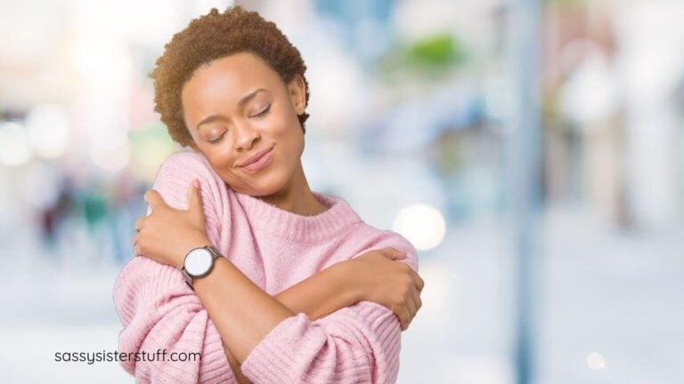 African American woman hugs herself and smiles.