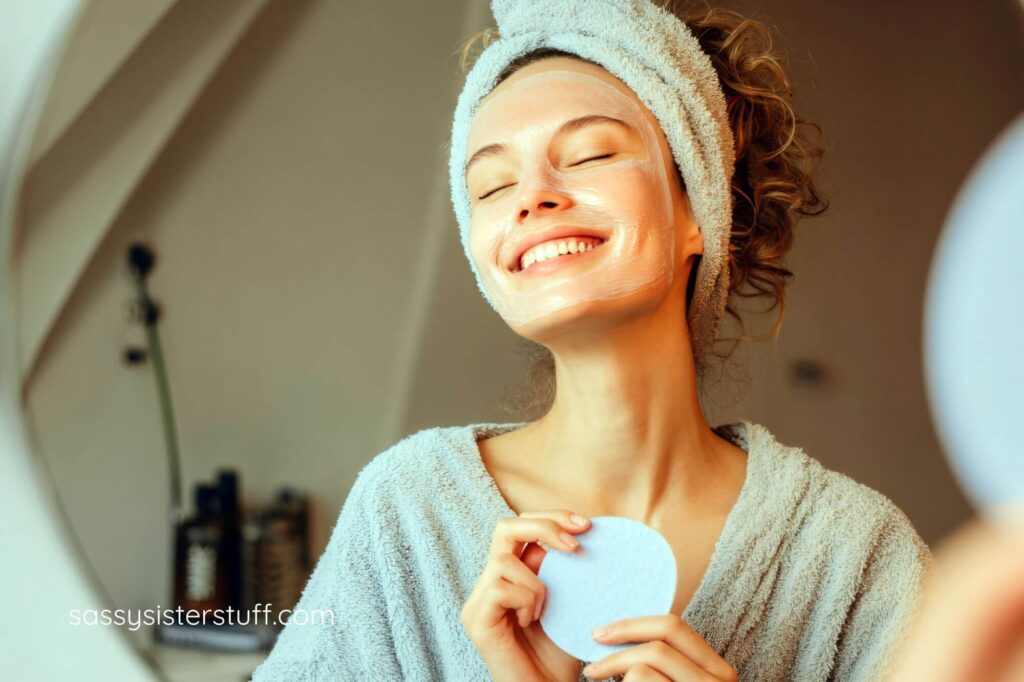 beautiful, happy woman looks in the mirrorr at herself as she does a spa day for self care Sunday.
