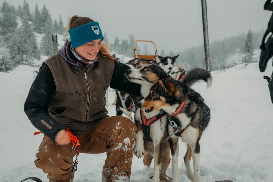 woman petting dogs in the snow.
