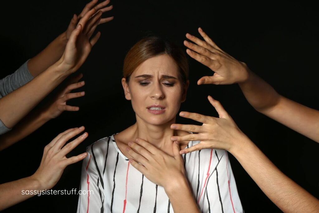 midlife woman having a panic attack and hands coming at her from all directions.