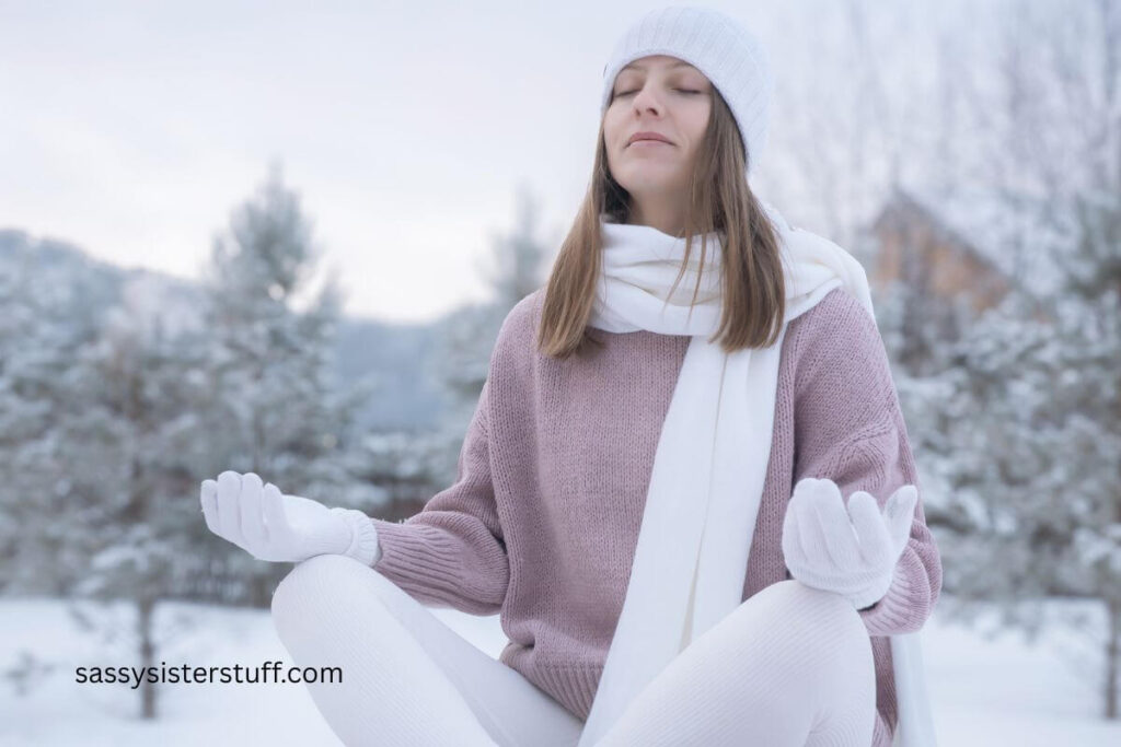 peaceful midlife woman sits in the snow and does yoga to reset, recharge, and get grounded.