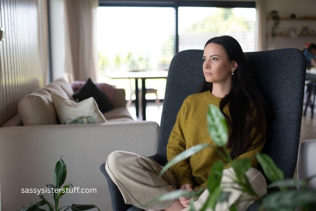 midlife woman sitting cross-legged staring out a window in serious contemplation about her situation.