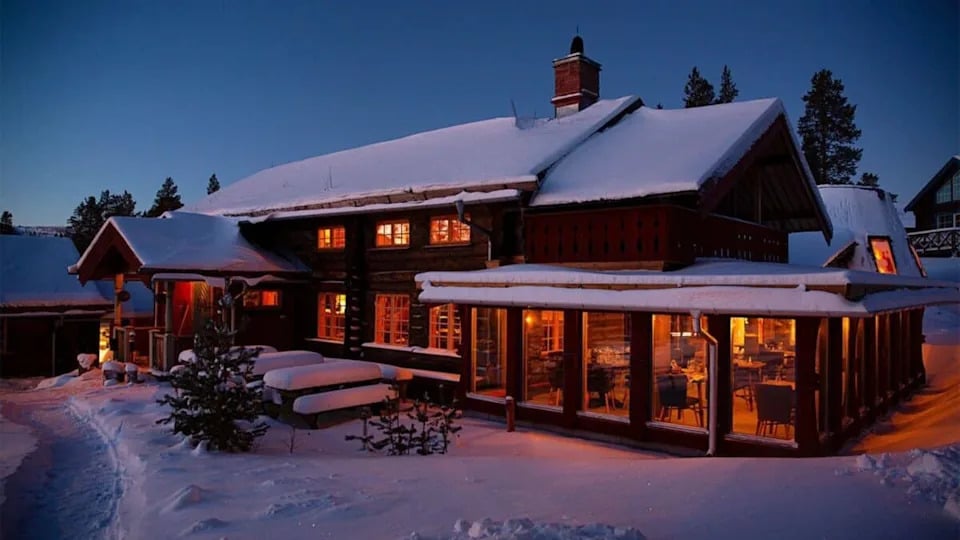 night view of a beautiful lodge lit up with lights in the snow.