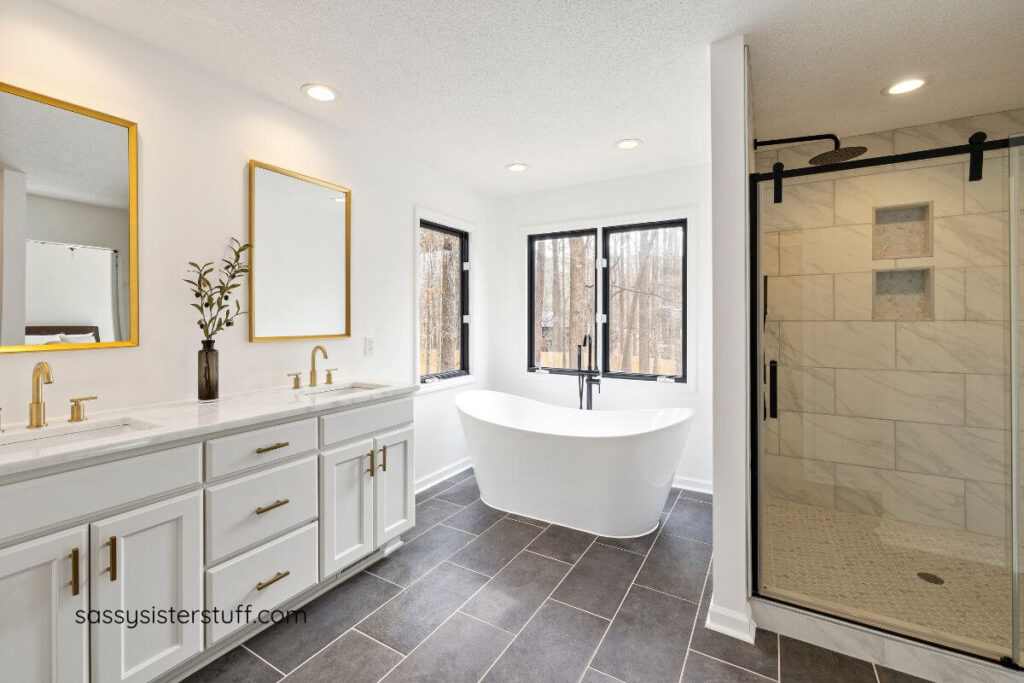 a bathroom designed in shades of white and gray with a soaking tub, shower stall, and two-sink vanity.