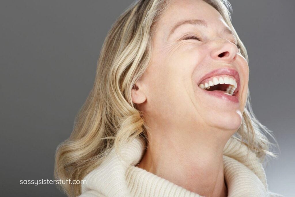 close up of midlife woman with blonde hair laughing out loud.