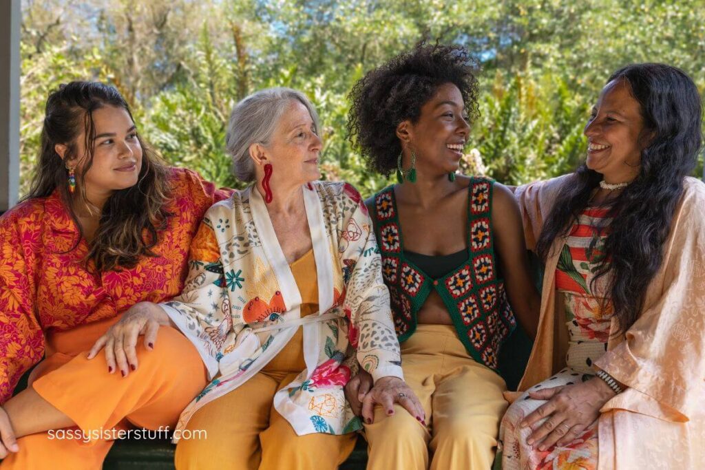 multicultural midlife women sitting on a bench laughing and talking.