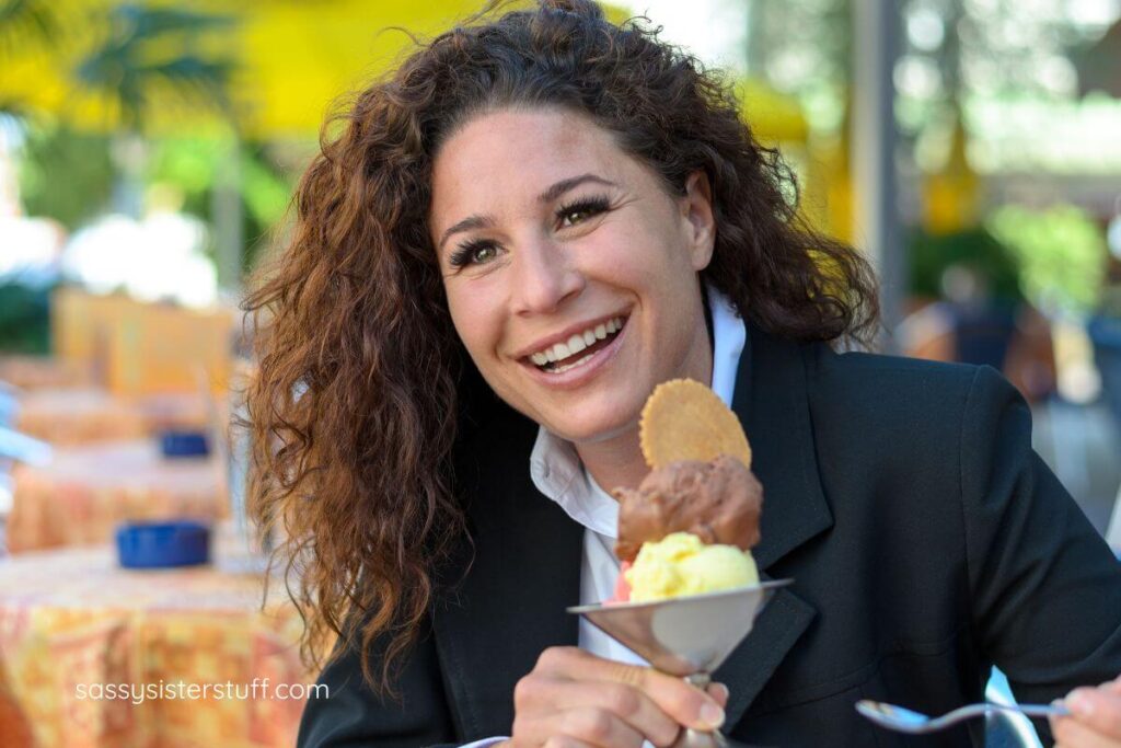 midlife woman joyfully eating an ice cream sundae for dinner.
