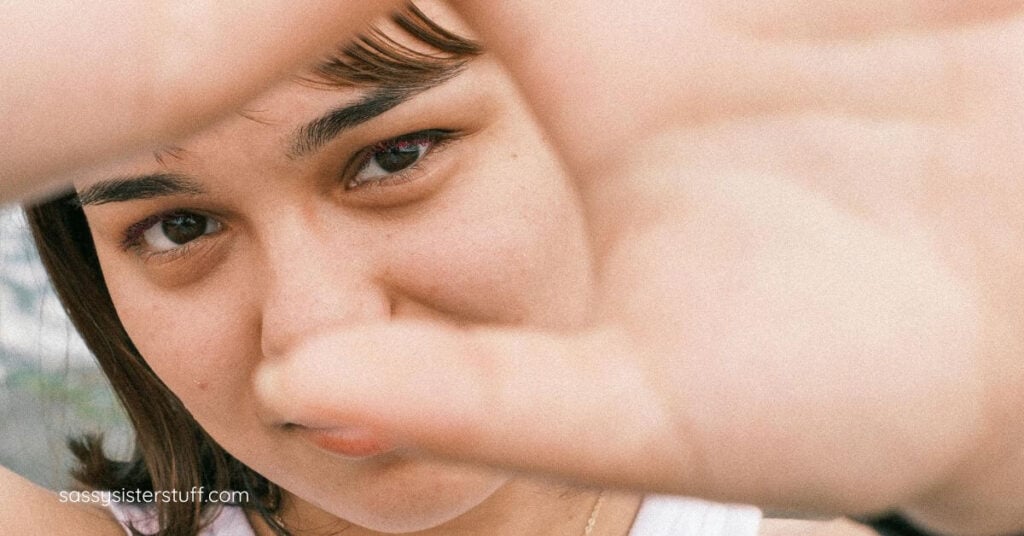 close up of a woman with her hands reached out in front of her face to indicate she has boundaries and backbone in midlife.