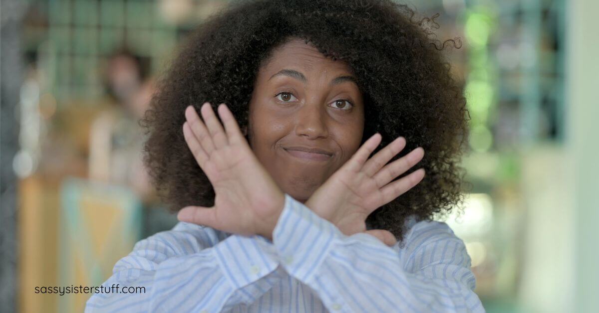 midlife woman with her hands forming an X up near her chin to show she has boundaries and backbone in midlife.