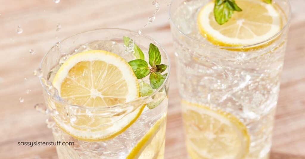 two glasses of water with lemon slices in them.