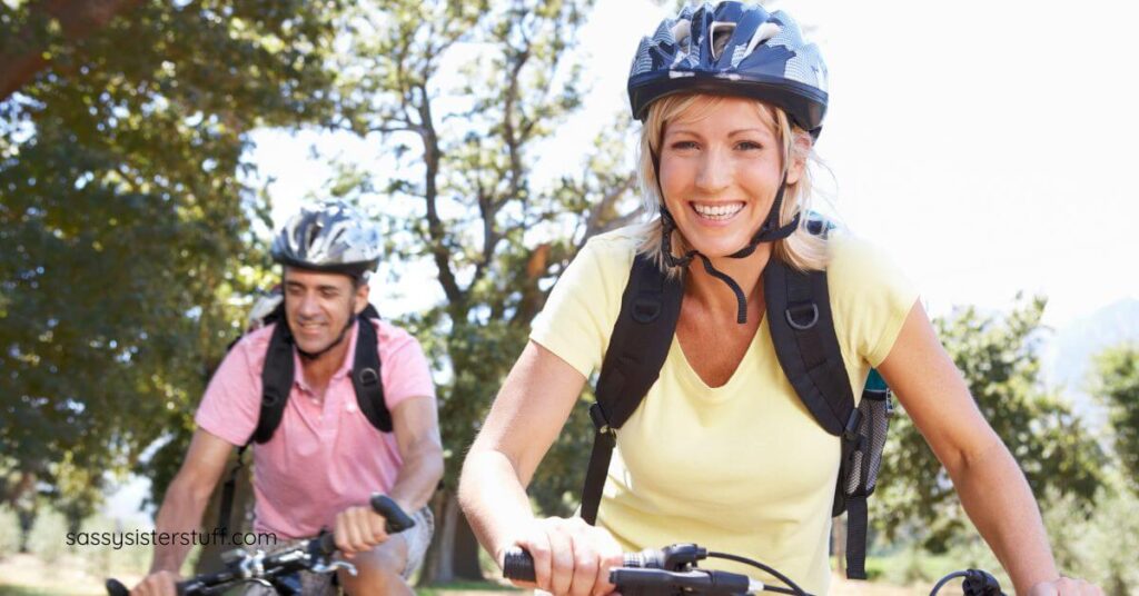 midlife woman and her male companion biking through the park.