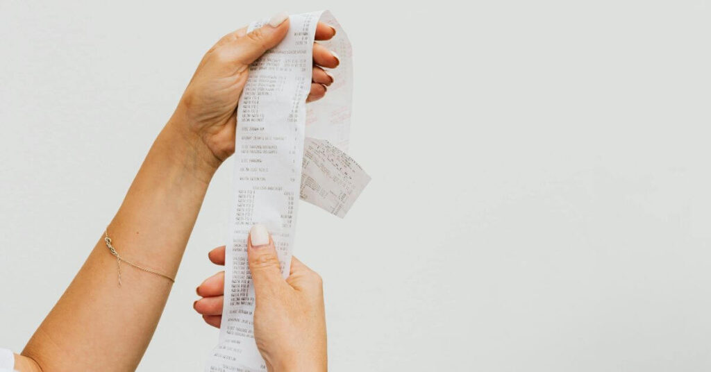 female hands holding up a receipt for a purchase.