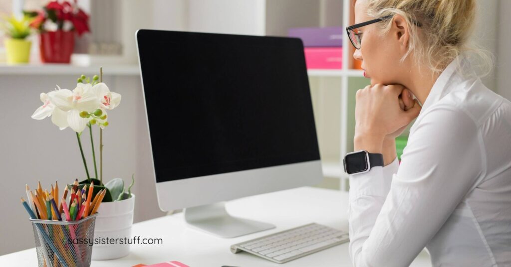 woman sitting at a desk staring at a black laptop screen considering a midlife career change.
