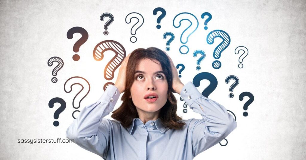 woman with her hands on her head looking UP and question marks all around her.