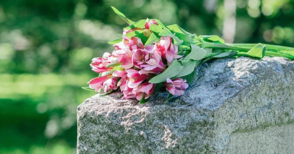 pink flowers laying on top of a tombstone.