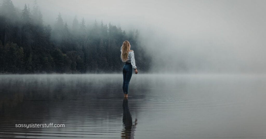 woman walking in the fog toward some trees reflecting about the in-between space she's in now.