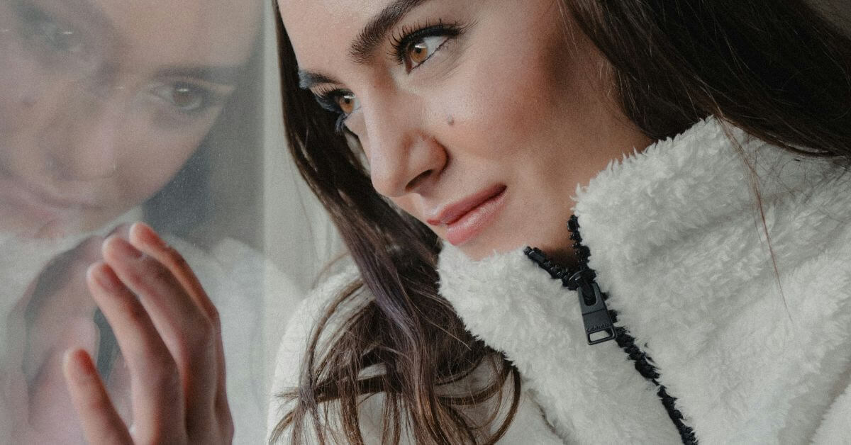 close up of woman looking out a window reflecting about the in-between space she's in now.