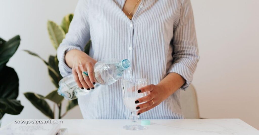 close up of woman pouring herself a glass of water to stay hydrated to help her menopause brain fog symptoms.