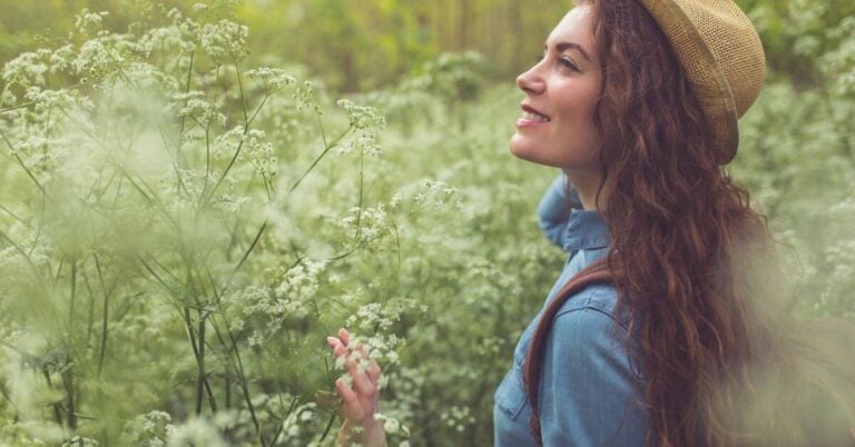 beautiful womanw who is doing 30 things to do to feel like yourself again is walking in a flower field and enjoying the beauty.