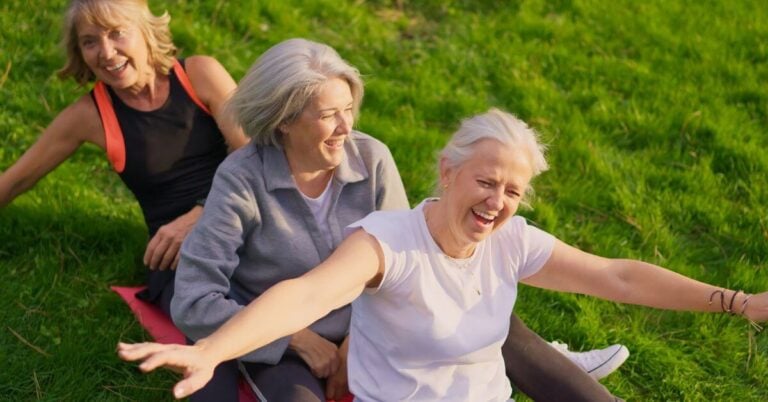 three midlife women pretending to slide down a hill on a mat to add adventure to everyday life.
