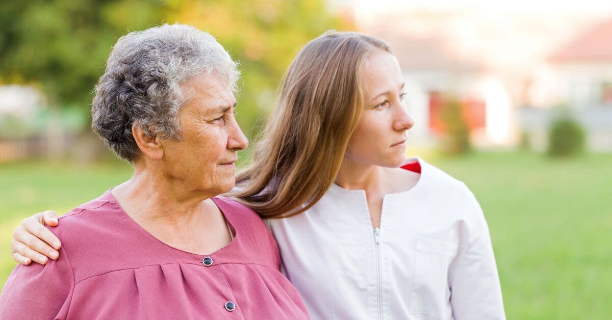 a young woman and her mom with dementia go for a walk in the park on a spring day.