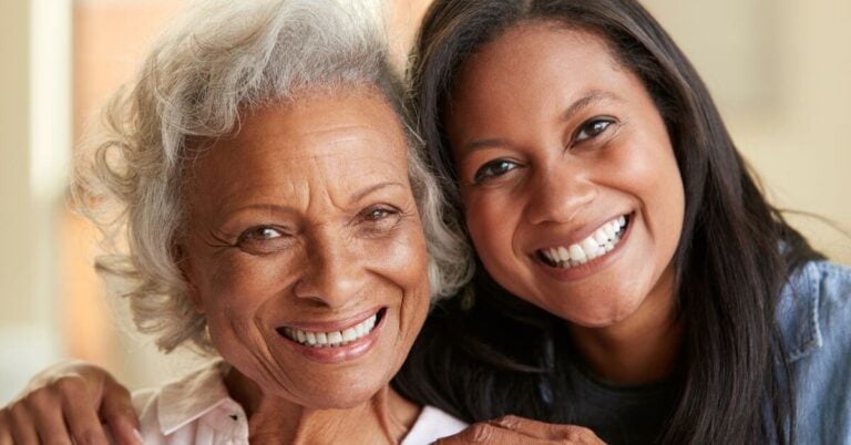 mother and adult daughter cheek-to-cheek, happy to be together on a vacation together.