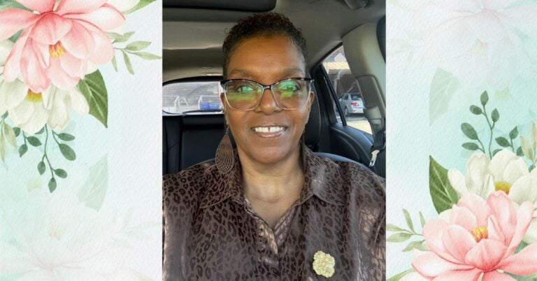 beautiful Black middle aged woman sits in her car confidently taking a picture.