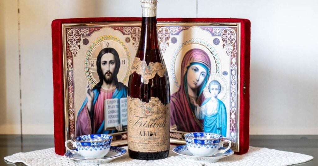 a collection of family heirlooms, tea cups, a wine bottle, and a bible.