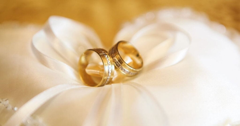 antique wedding rings laying on a white pillow.
